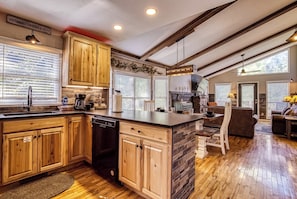 A spacious kitchen with wooden cabinets, a dishwasher, and a large island. - Family Getaway Close to Parkway-w/ Theater and Game Room (Pigeon Forge)