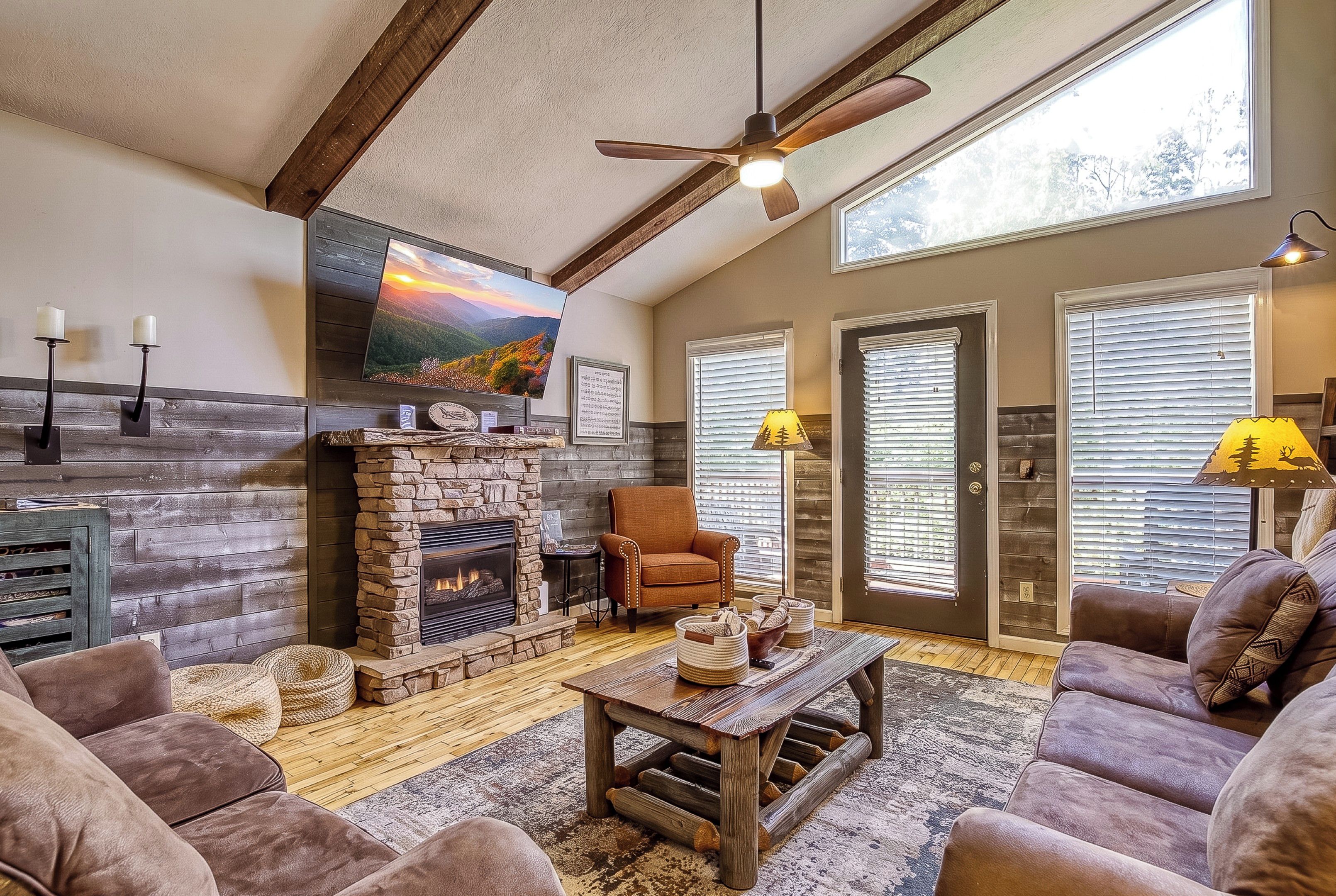 A cozy living room with a fireplace, comfortable seating, and a large window with blinds.