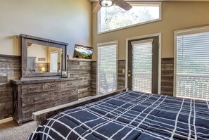 A bedroom with a large bed, a dresser, a mirror, and a ceiling fan.
