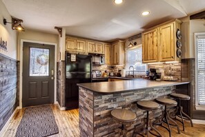 A kitchen with a central island, wooden cabinets, a refrigerator, and a patterned rug.