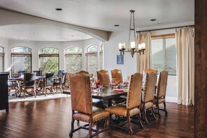 A dining room with a large wooden table, leather chairs, and a chandelier.