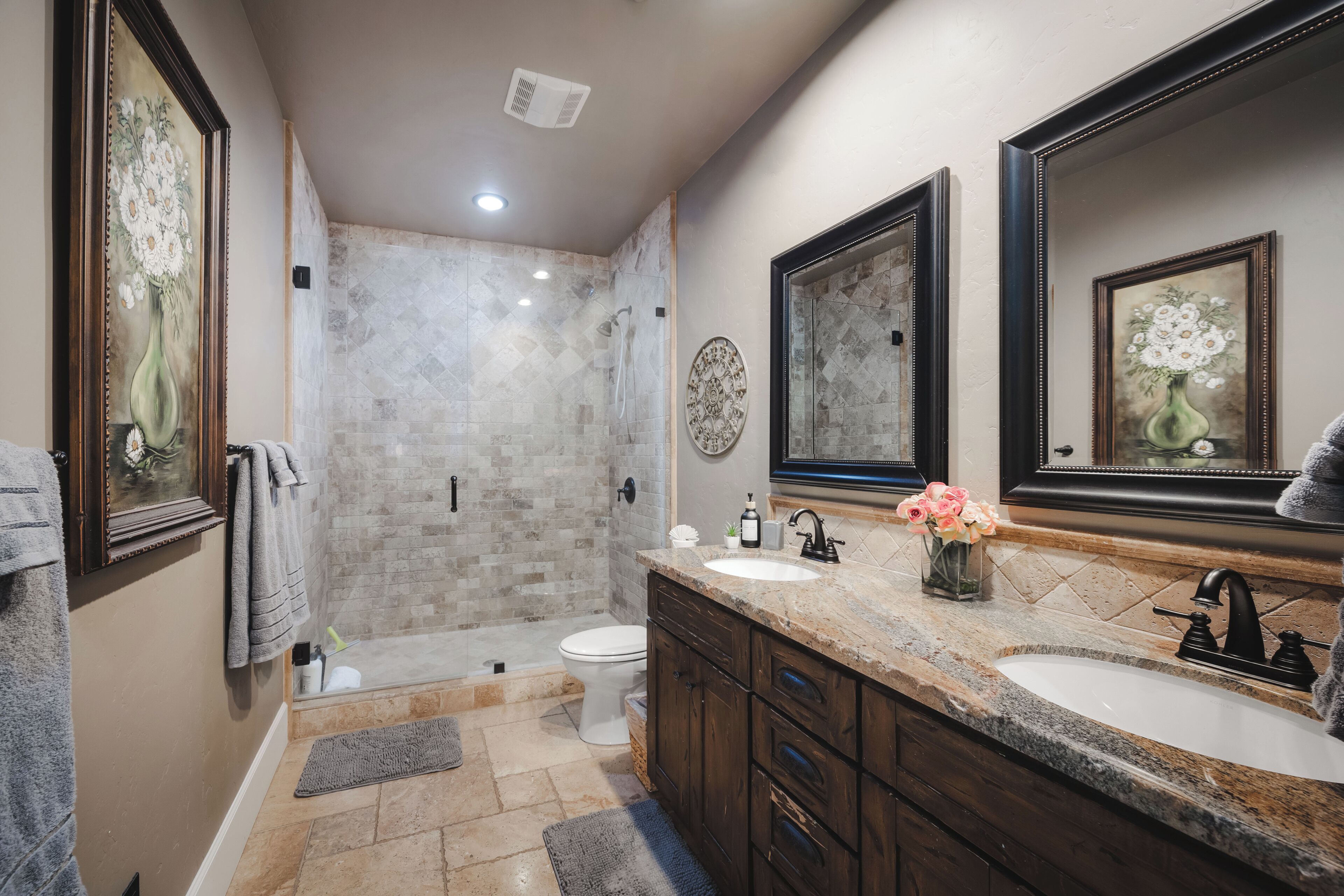 A bathroom with a shower, toilet, vanity with a sink, and two large mirrors.