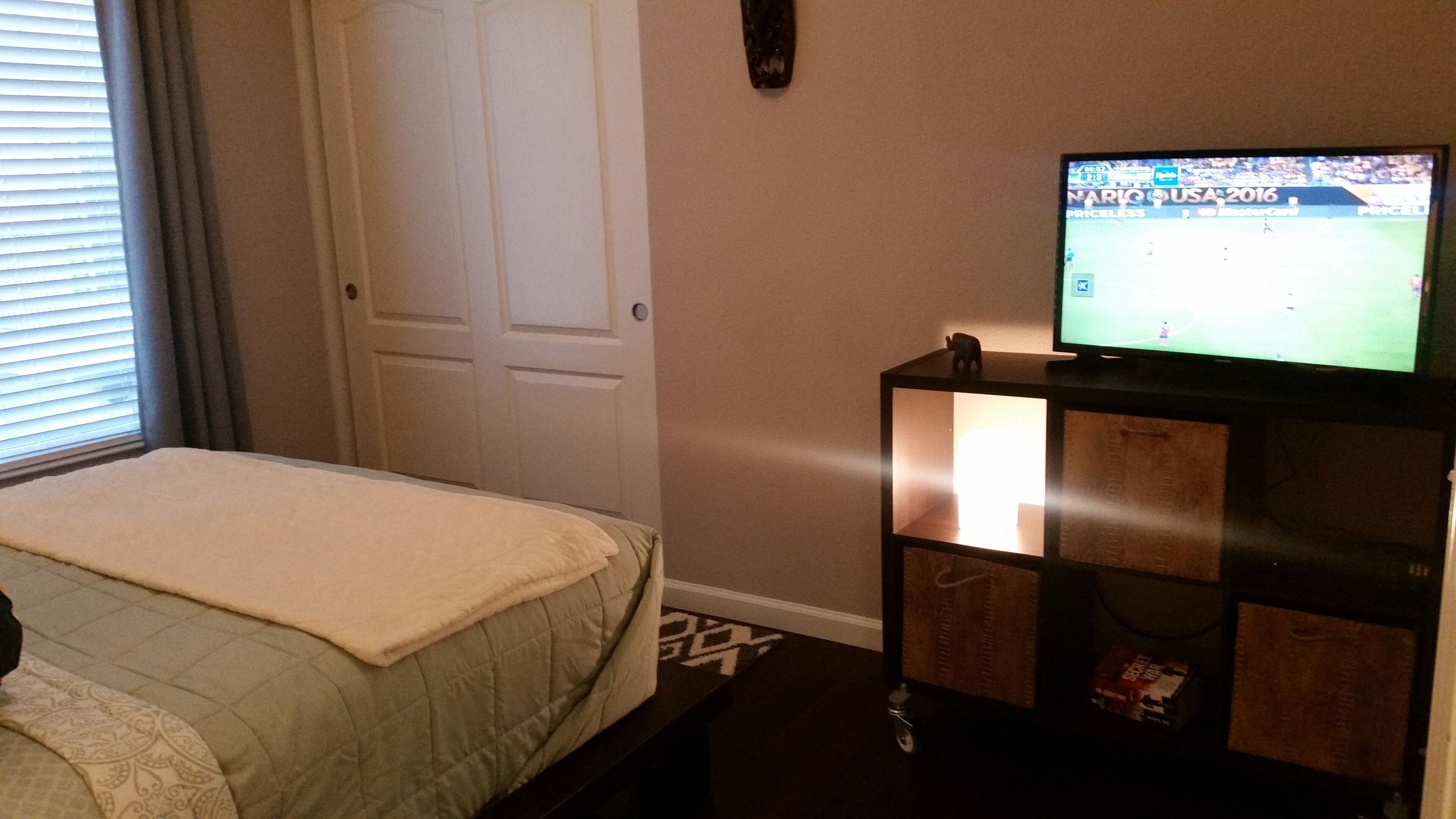 Ein Hotelzimmer mit einem Bett, einem Fernseher auf einem Schrank und einer Tür.