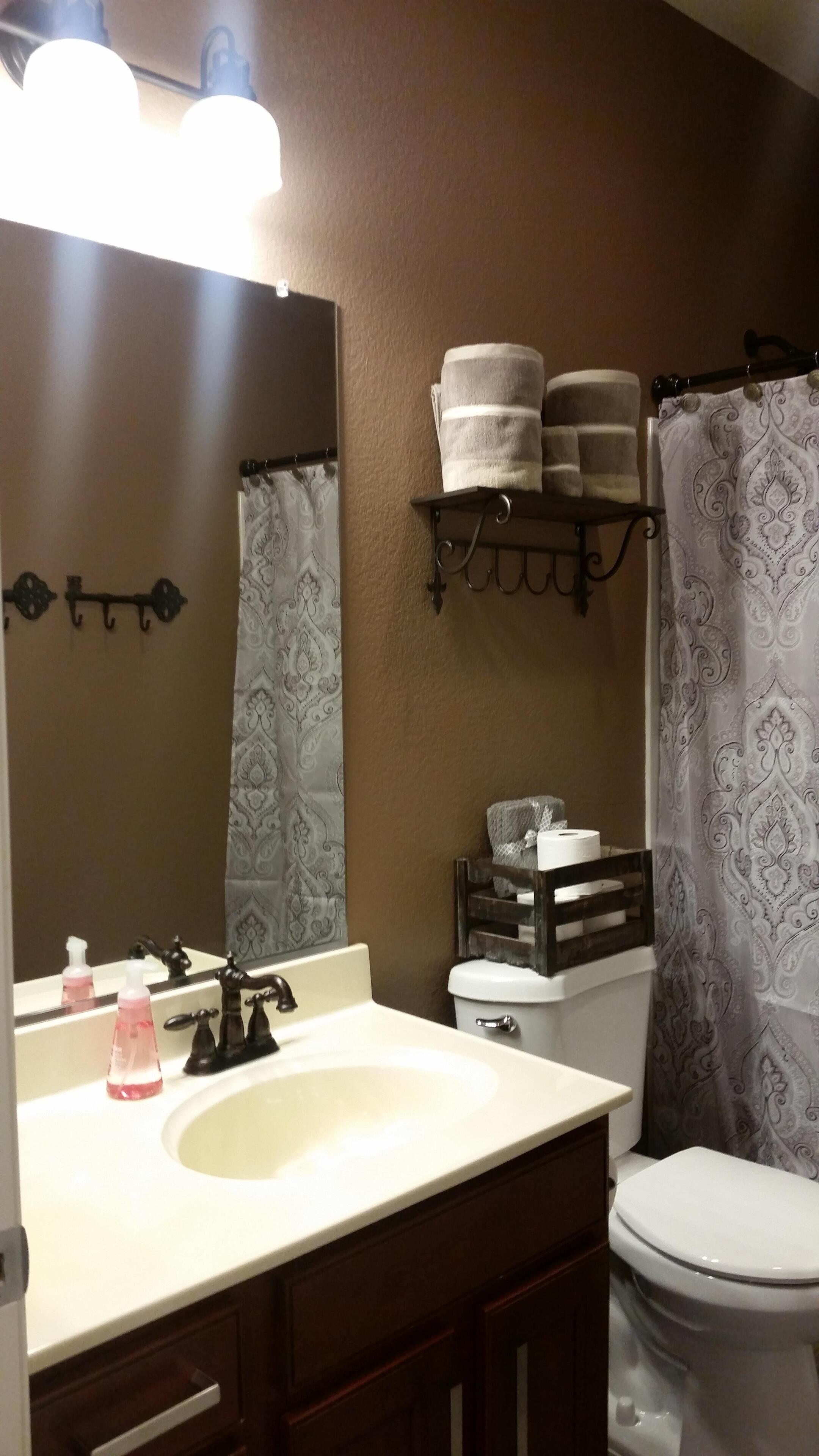 Un baño con lavamanos blanco, muebles de madera oscura, un espejo, inodoro y cortina de ducha.