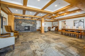 A spacious living area with a stone fireplace, wooden beams, and a large dining table.
