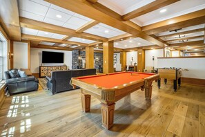 A spacious indoor area with a pool table, a sofa, and a television.