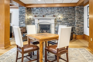 A dining area with a stone fireplace, wooden table, and leather chairs.