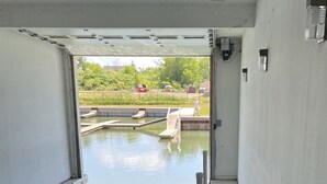 Une rampe d’accès pour bateaux menant à une étendue d’eau calme, avec un kayak et une planche à pagaie amarrés à proximité.
