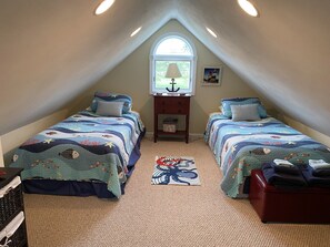A bedroom with two beds, a window, a nightstand, and a rug.
