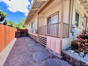 A wooden deck with a stone pathway leading to a building with a balcony.