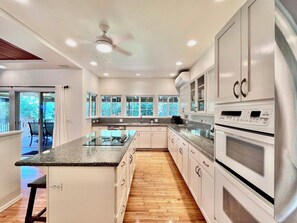 A modern kitchen with a central island, built-in appliances, and large windows.