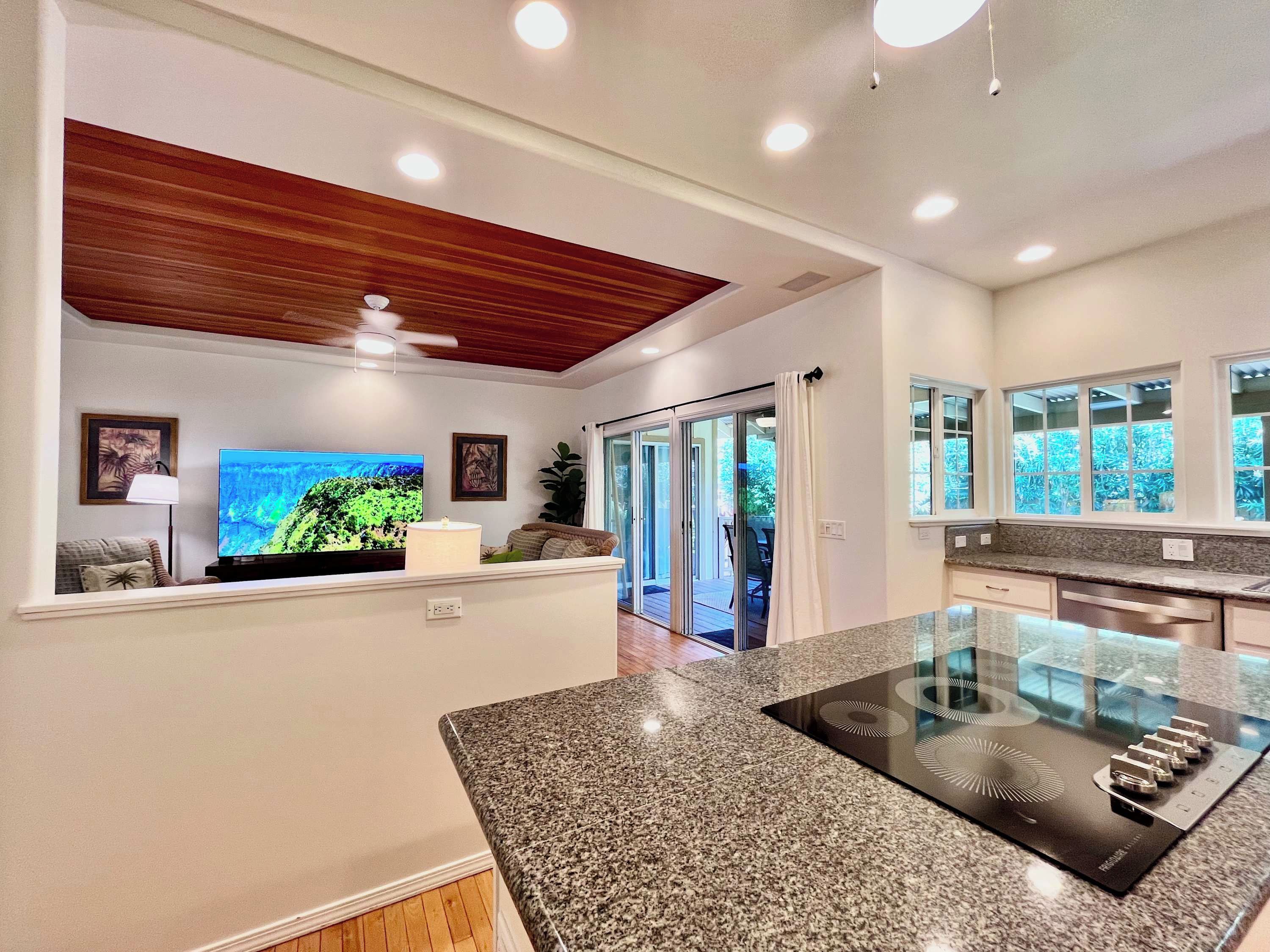 A modern kitchen with a granite countertop, a built-in stove, and a sliding glass door leading to a patio.