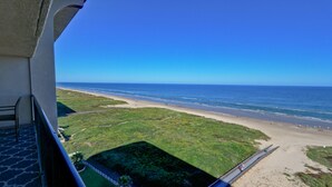 A view from a balcony overlooking a beach with a clear sky.