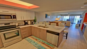 A modern kitchen with stainless steel appliances, a central island with a sink, and a dining area with a view.