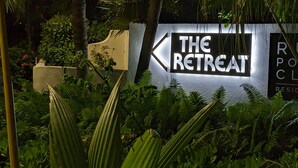 Señal de 'The Retreat' con una flecha indicando dirección, rodeada de vegetación exuberante.