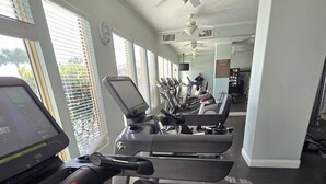 Un gimnasio con cintas de correr, bicicletas estáticas y un espejo grande.
