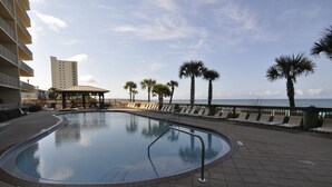 Una piscina con solárium, palmeras y vista al océano.