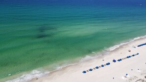 Una playa con agua turquesa cristalina, una orilla de arena y hileras de sillas azules.