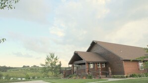 A rustic log cabin with a porch and a view of the surrounding landscape. - Buck Run Lodge - Conference Facility, Nature's Own Retreat , (Anita)