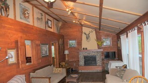 A cozy living room with wooden walls, a stone fireplace, a television, and a comfortable seating area. - Buck Run Lodge - Conference Facility, Nature's Own Retreat , (Anita)