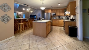 Una cocina moderna con una isla central, armarios de madera y un refrigerador de acero inoxidable.