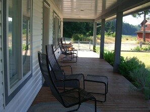 Relax on the covered porch with comfortable seating and a small table, taking in the views of the surrounding landscape.