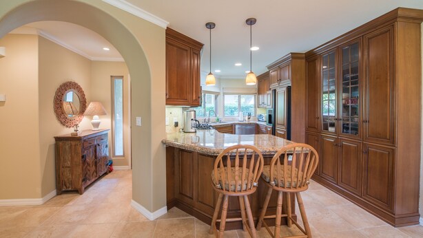 A kitchen with wooden cabinets, a marble countertop, and two bar stools. - Single Story Condo, All New w/BBQ at Blacklake w/3 Golf Courses (Nipomo)