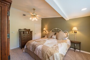 Ein Schlafzimmer mit Bett, Kommode, Nachttischen und Deckenventilator.