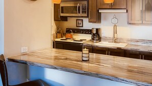 Una cocina moderna con una isla central, taburetes de bar e iluminación colgante.