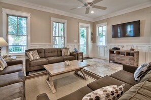 A spacious living room with a large sectional sofa, a wooden coffee table, and a TV mounted on the wall.