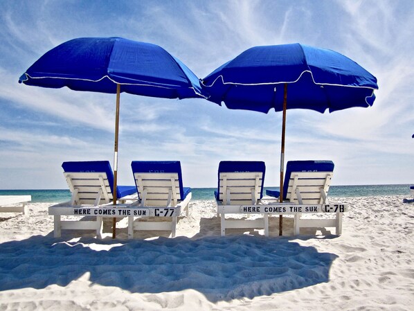 Four beach chairs with blue umbrellas and white cushions, labeled "Here comes the sun" and "Here comes the sun."