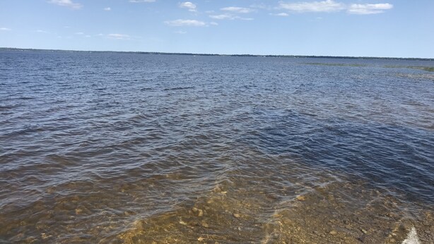 A calm body of water with clear shallow areas revealing rocks and pebbles. - Quaint getaway to unwind and relax.  (Manistique)