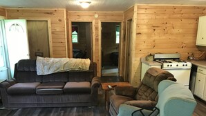 A cozy cabin interior with a dark brown sofa, a light blue armchair, and a wooden dining table. - Quaint getaway to unwind and relax.  (Manistique)