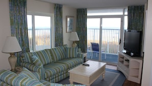 Un salon avec des canapés à rayures, une table basse, un téléviseur et un balcon avec vue.