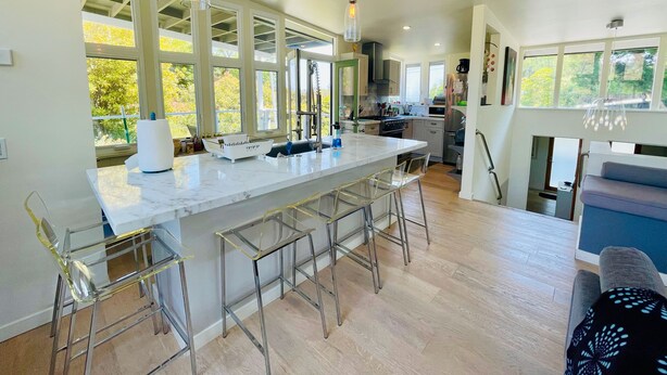 Een moderne keuken met een groot eiland, barstoelen en hanglampen.
