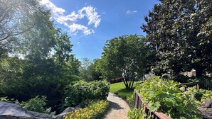 A pathway flanked by greenery and a wooden fence, leading to a grassy area with trees. - Riverstone 2BR - River & Mountain Views / 5 min to Dollywood & Ripken (Pigeon Forge)