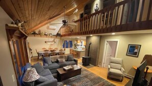 Un'ampia zona giorno con soffitto alto, una sala da pranzo e una scala che conduce al piano superiore.