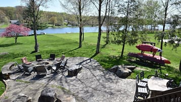 Une terrasse avec un sol en pierre, du mobilier d’extérieur et une vue sur un lac.