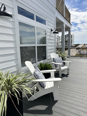 Um deck com cadeiras Adirondack e um vaso de planta.