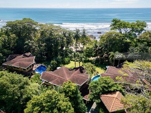 A coastal property with multiple buildings, a swimming pool, and lush greenery.