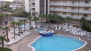 Zona de piscina hotelera con varias piscinas, tumbonas y palmeras.