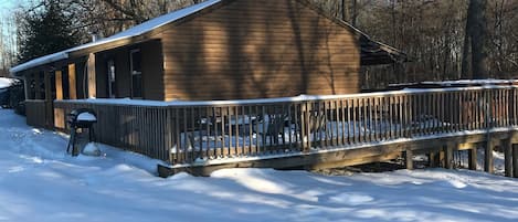 A wooden cabin with a covered porch and a snow-covered deck.