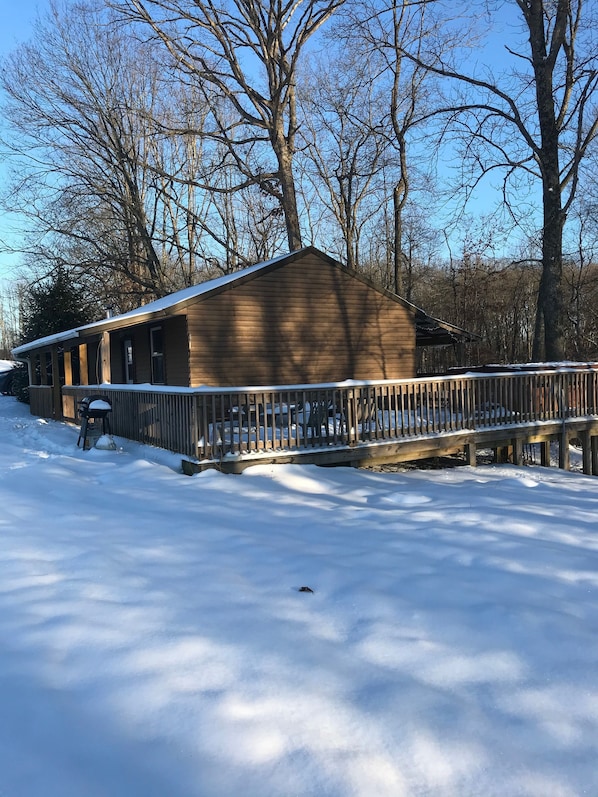 A wooden cabin with a covered porch and a snow-covered deck.