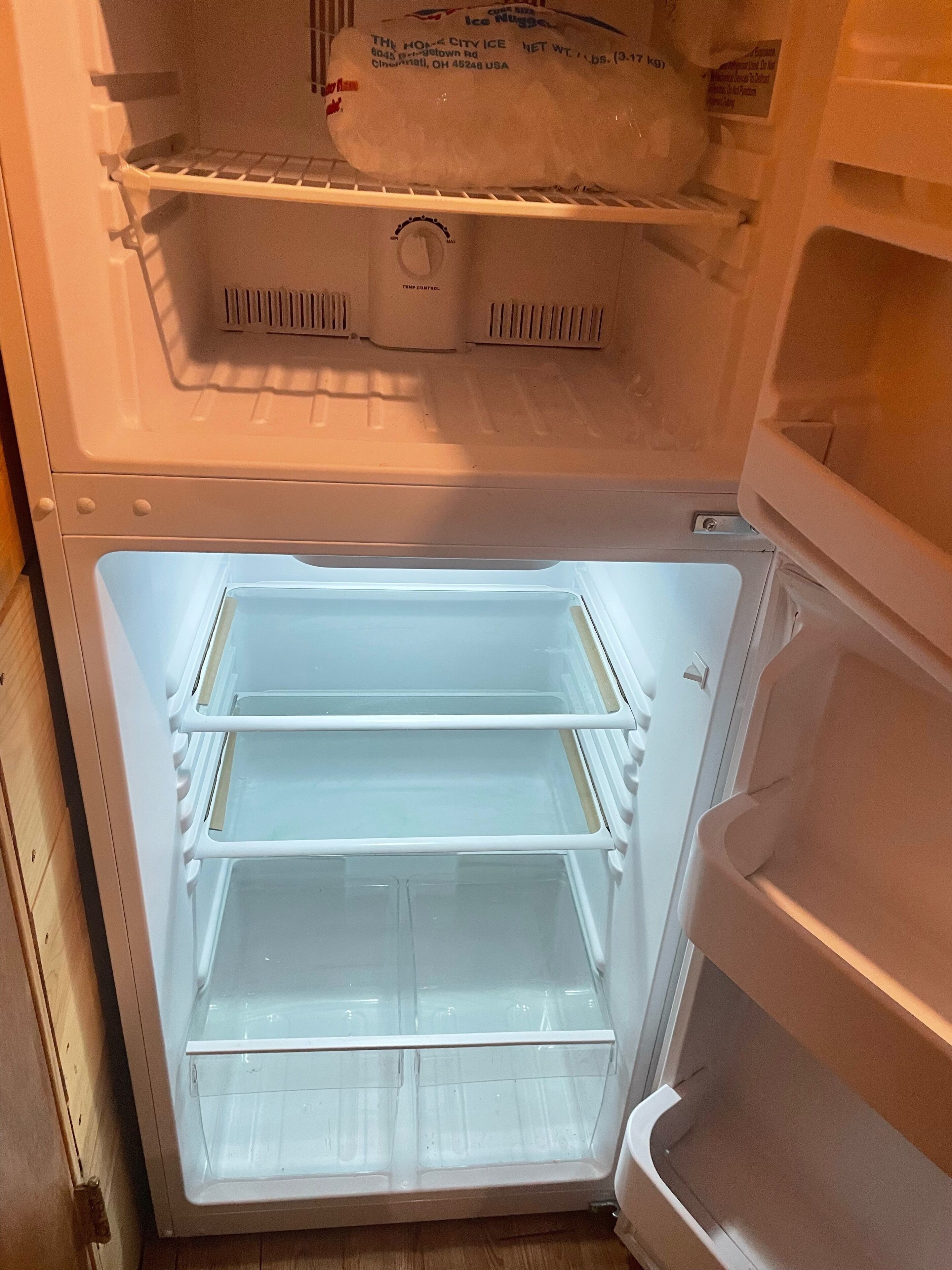 Un refrigerador abierto con varios estantes y un compartimento congelador.