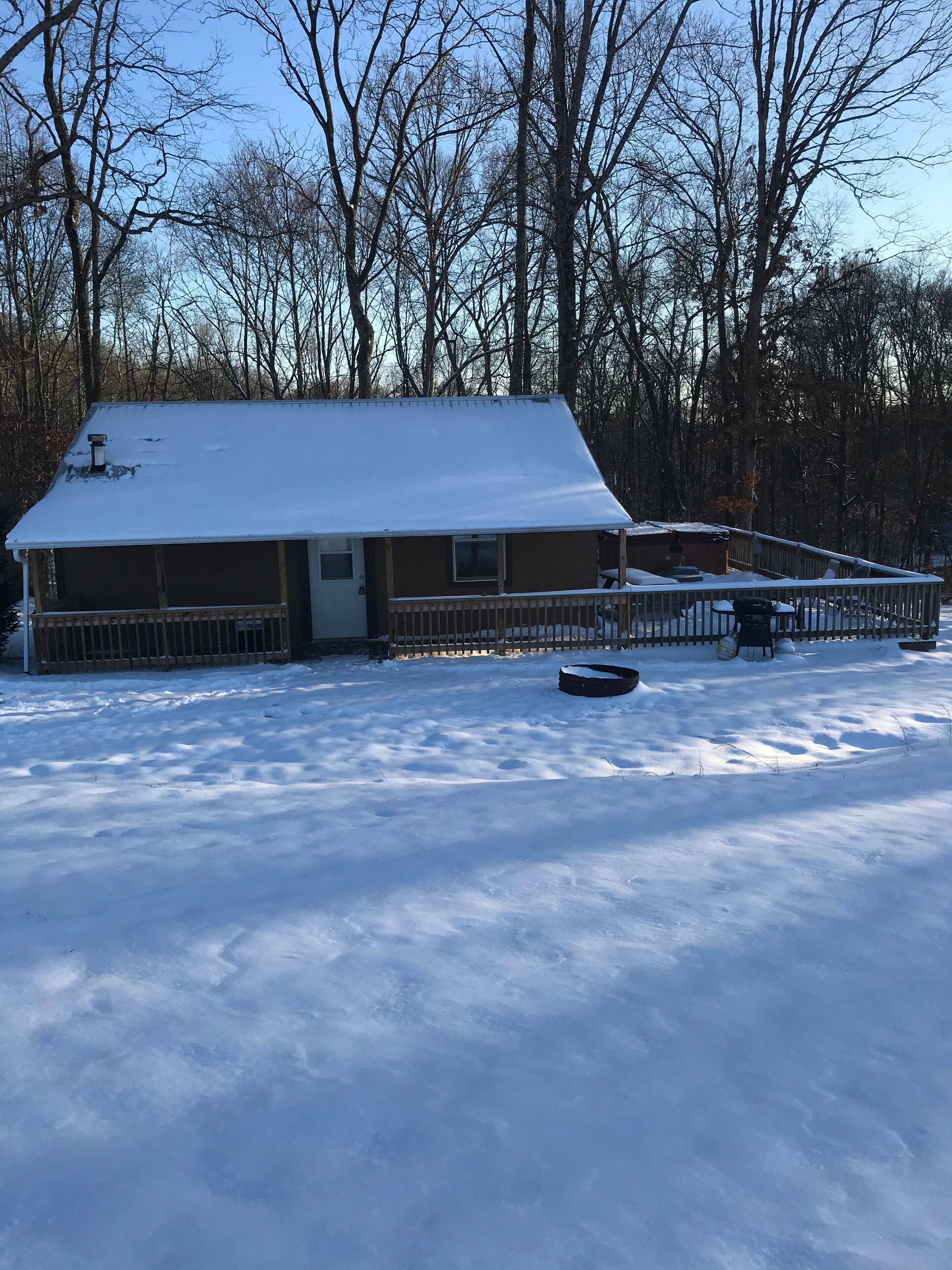 Un edificio cubierto de nieve con un deck cercado, rodeado de árboles.