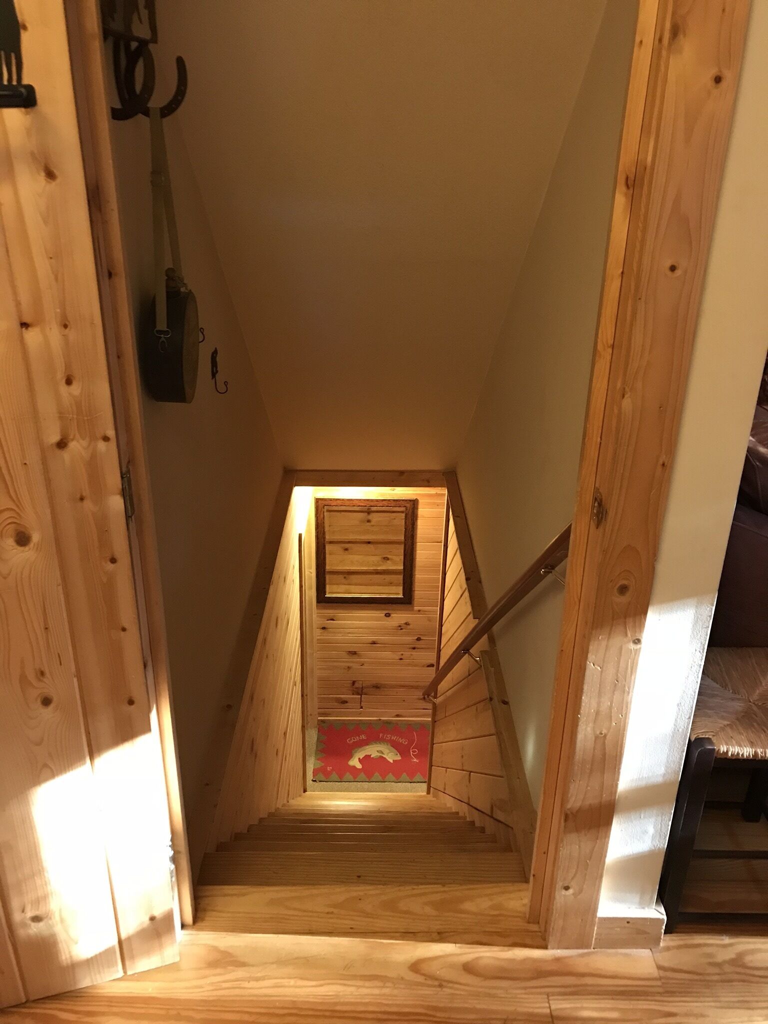 A wooden staircase leading to a loft bedroom with a sloped ceiling and a small window.