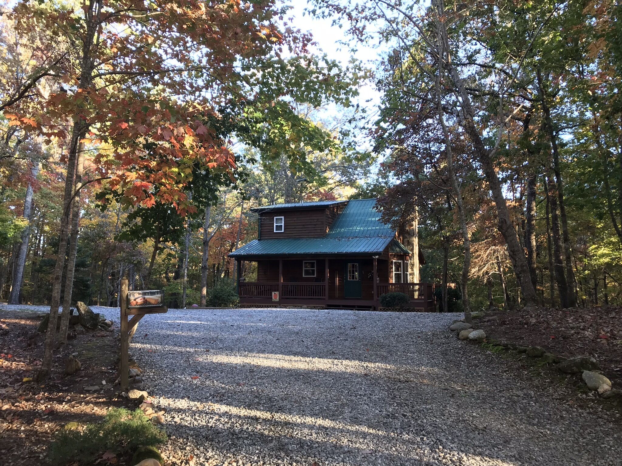 A rustic cabin with a metal roof, surrounded by trees with autumn foliage.