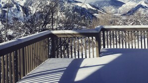 A snow-covered mountain landscape with a wooden deck and railing.