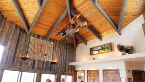 A rustic interior with exposed wooden beams, a decorative wall hanging, and a mounted airplane model.