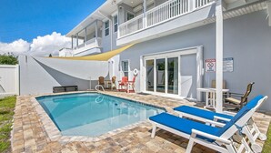 A swimming pool with lounge chairs, a covered patio, and a two-story building with a balcony. - 200 Yards toCocoa Beach, 4 bd, 3 1/2 Bath, Private Pool (Cocoa Beach)